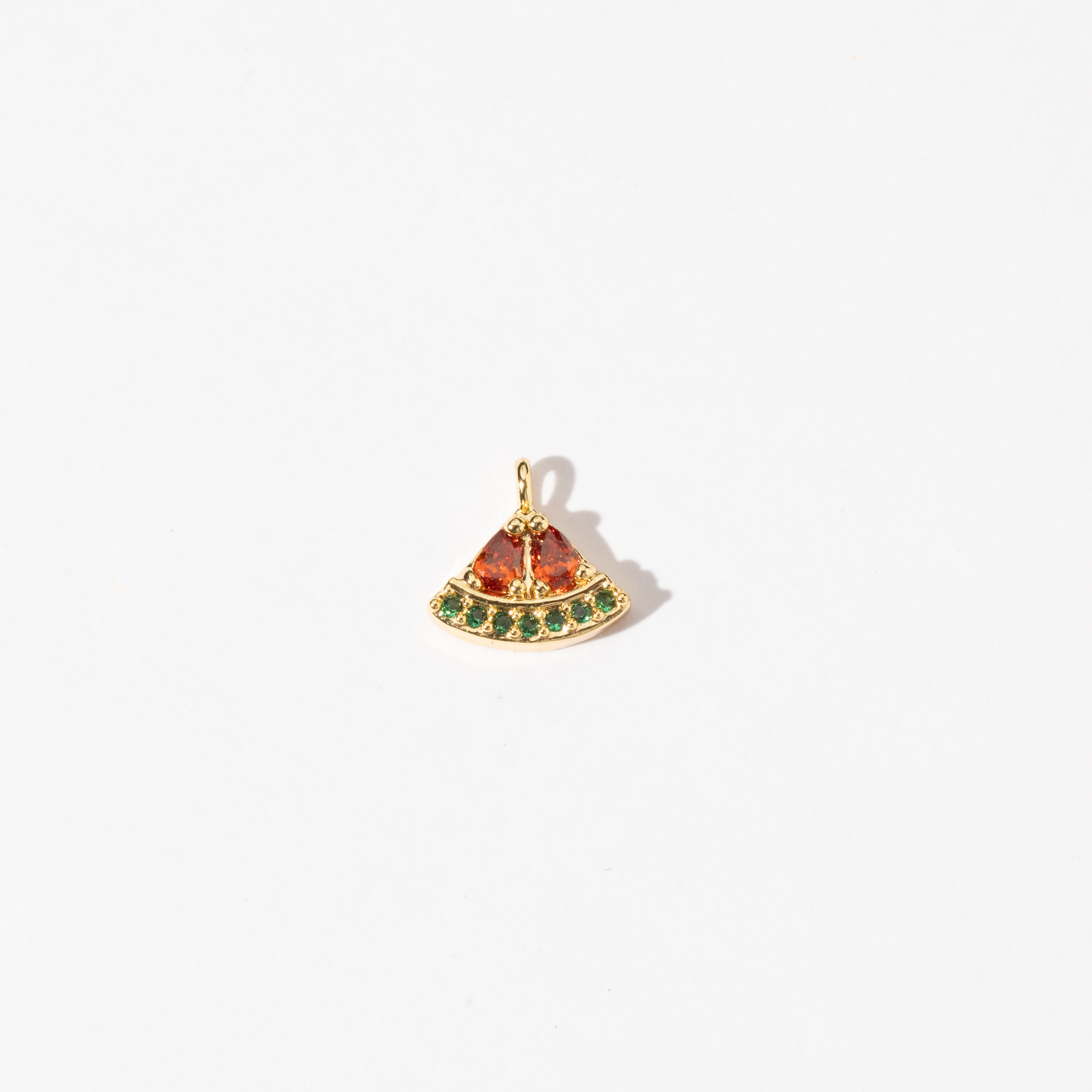 A gold plated personalized stainless steel charm in the shape of a watermelon slice, adorned with red and green zirconia stones.
