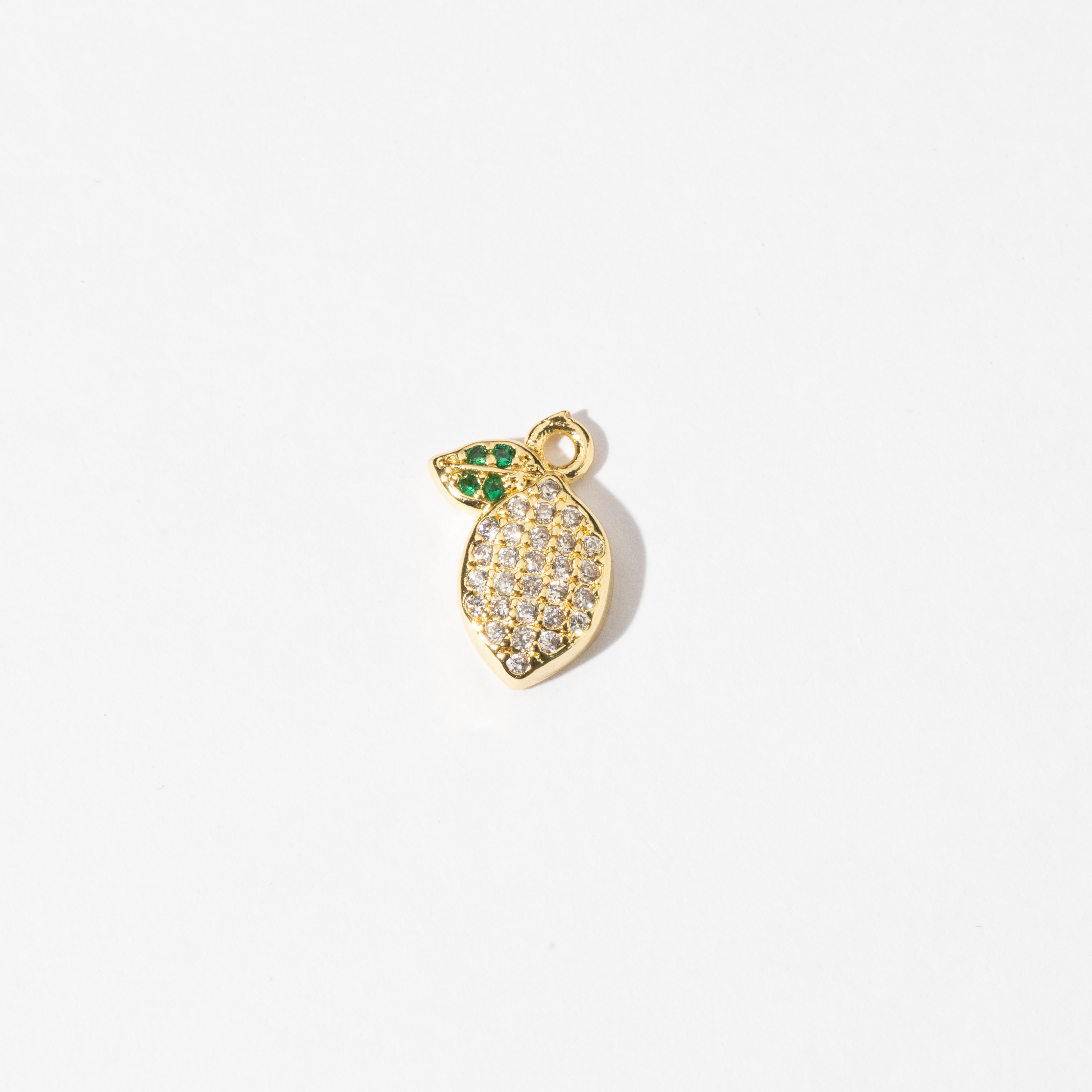 A Personalized gold-plated charm Jewelry in the shape of a lemon, adorned with clear zirconia stones and green gem leaves.