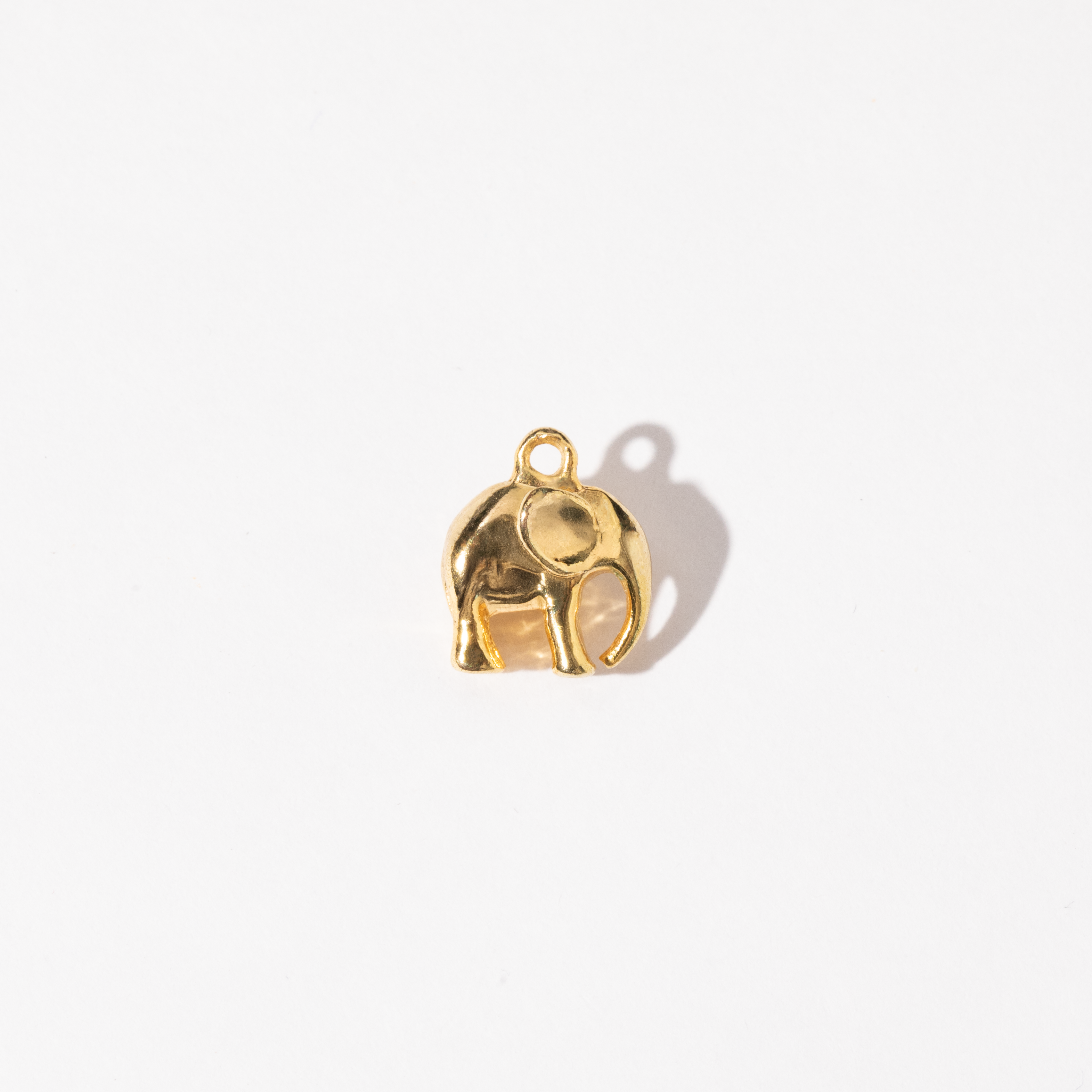 A gold-colored metal charm shaped like an elephant.