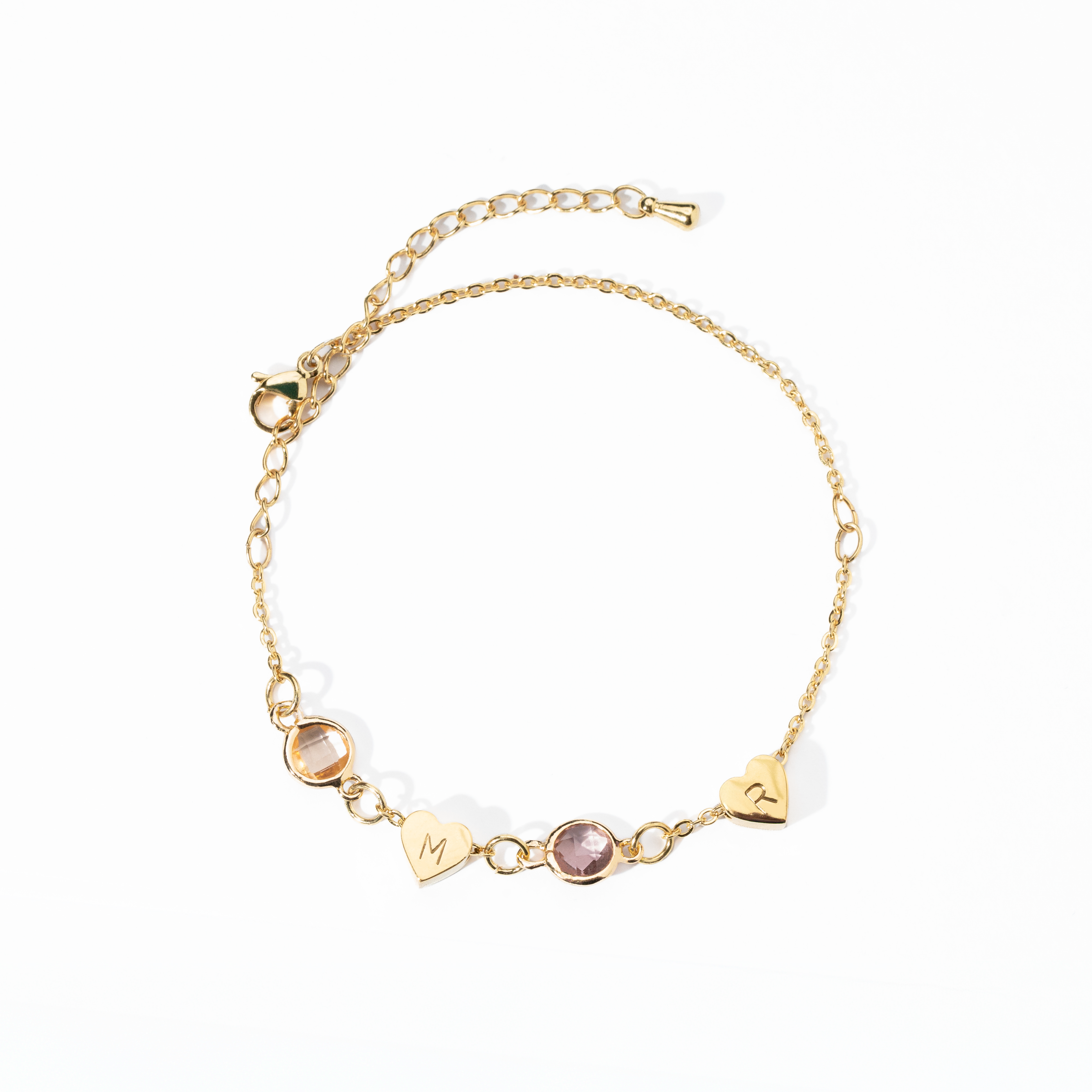 A personalized gold-colored bracelet featuring a heart-shaped charm and a birthstone, attached to a chain with a extender chain.