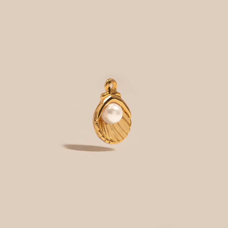 A gold-colored pearl shell charm against a light background.