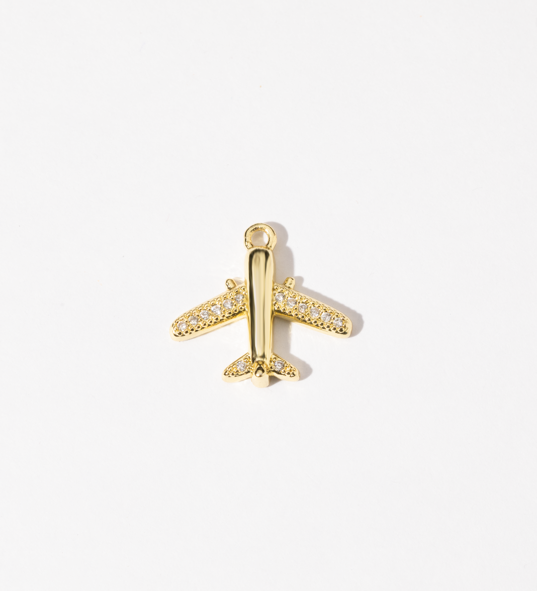 A gold-colored airplane-shaped charm with cubic zirconia stones adorning its body.