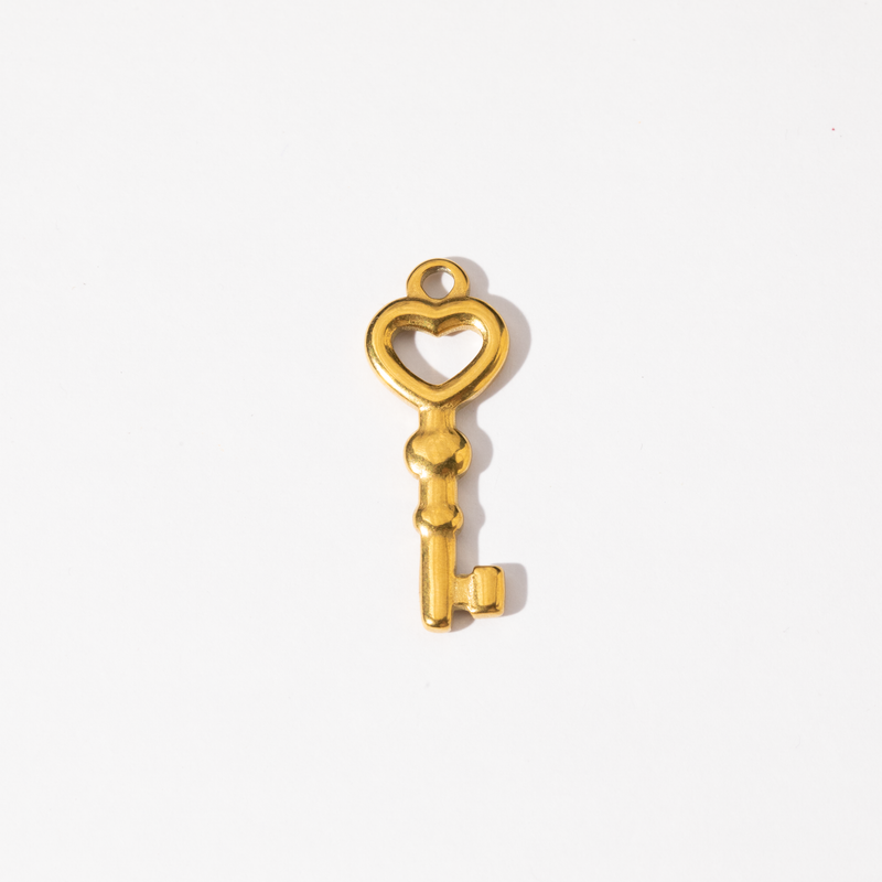 A gold-plated stainless steel charm in the shape of a key with a heart-shaped design at the top.