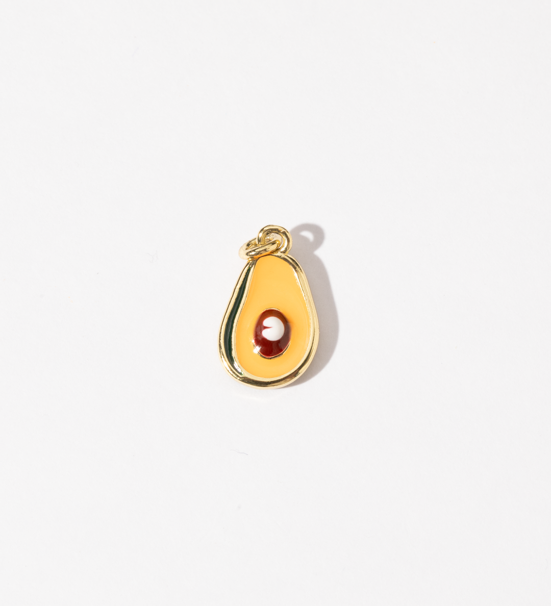 A gold-plated stainless steel charm in the shape of a half-avocado design with a polished seed at the center