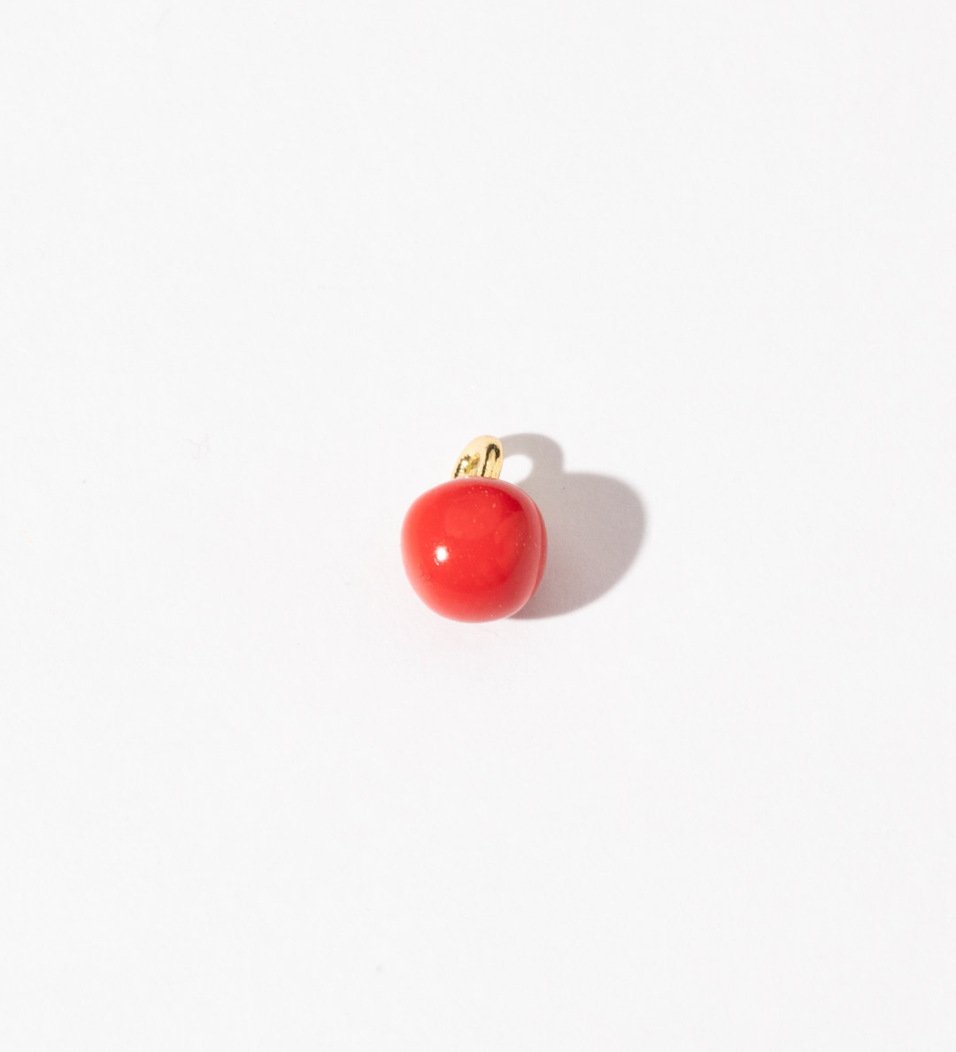 A gold-plated stainless steel charm with a smooth, rich red surface and golden accents, resembling a cherry tomato.