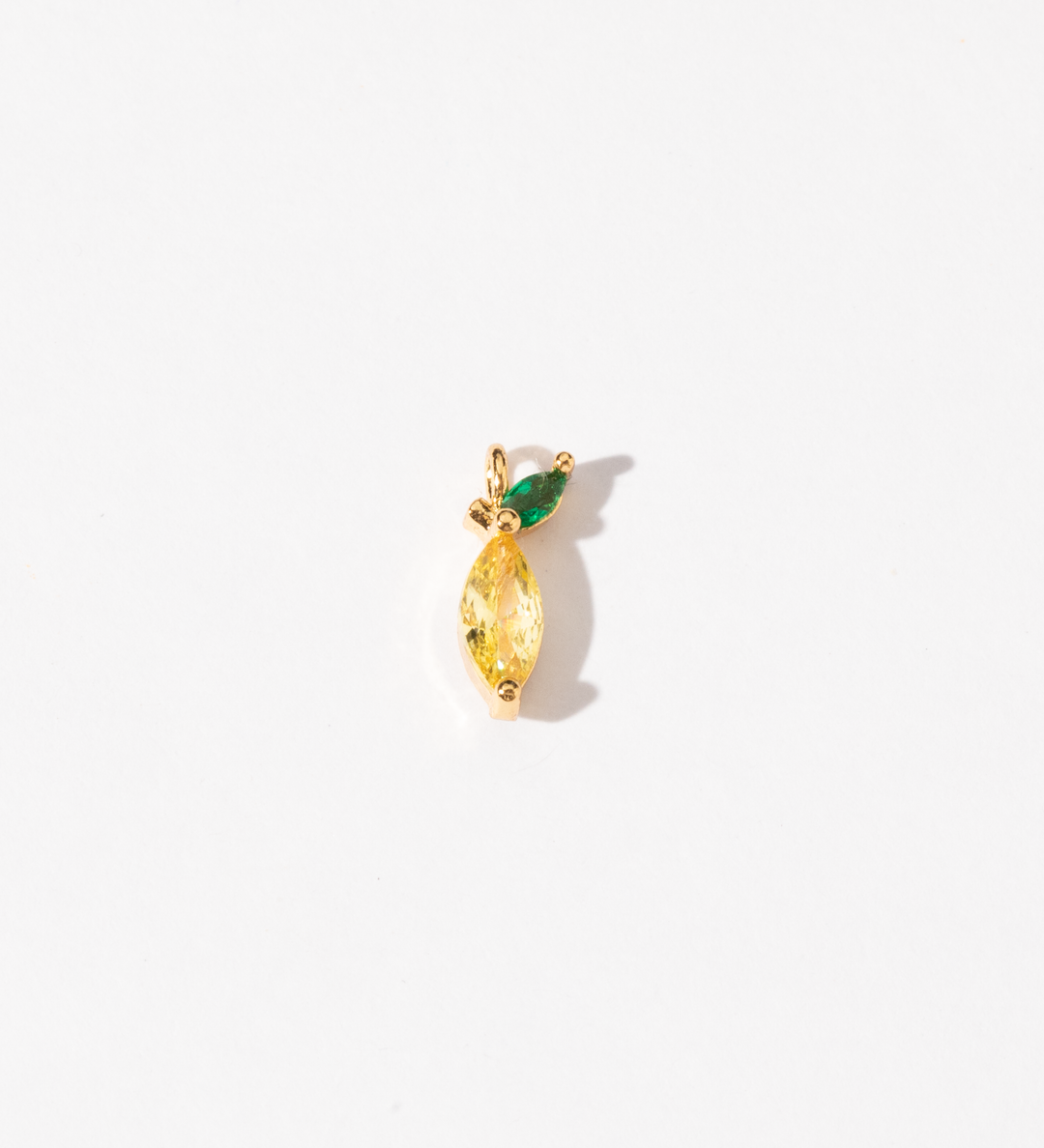 A custom made gold plated stainless steel charm featuring a yellow lemon-shaped zirconia with a green marquise-cut zirconia leaf accent.