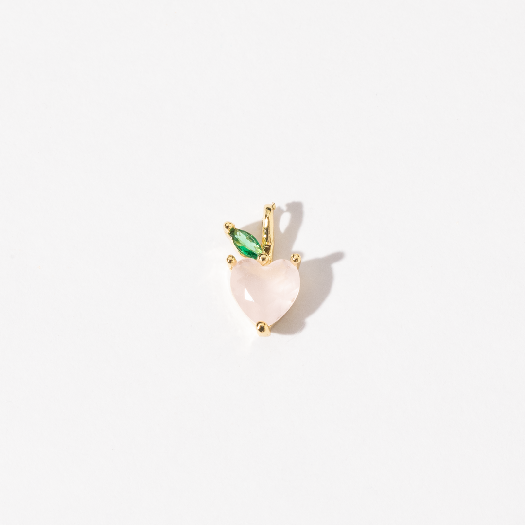 A gold plated stainless steel handmade charm with a soft pink heart-shaped peach and a single green zirconia leaf.