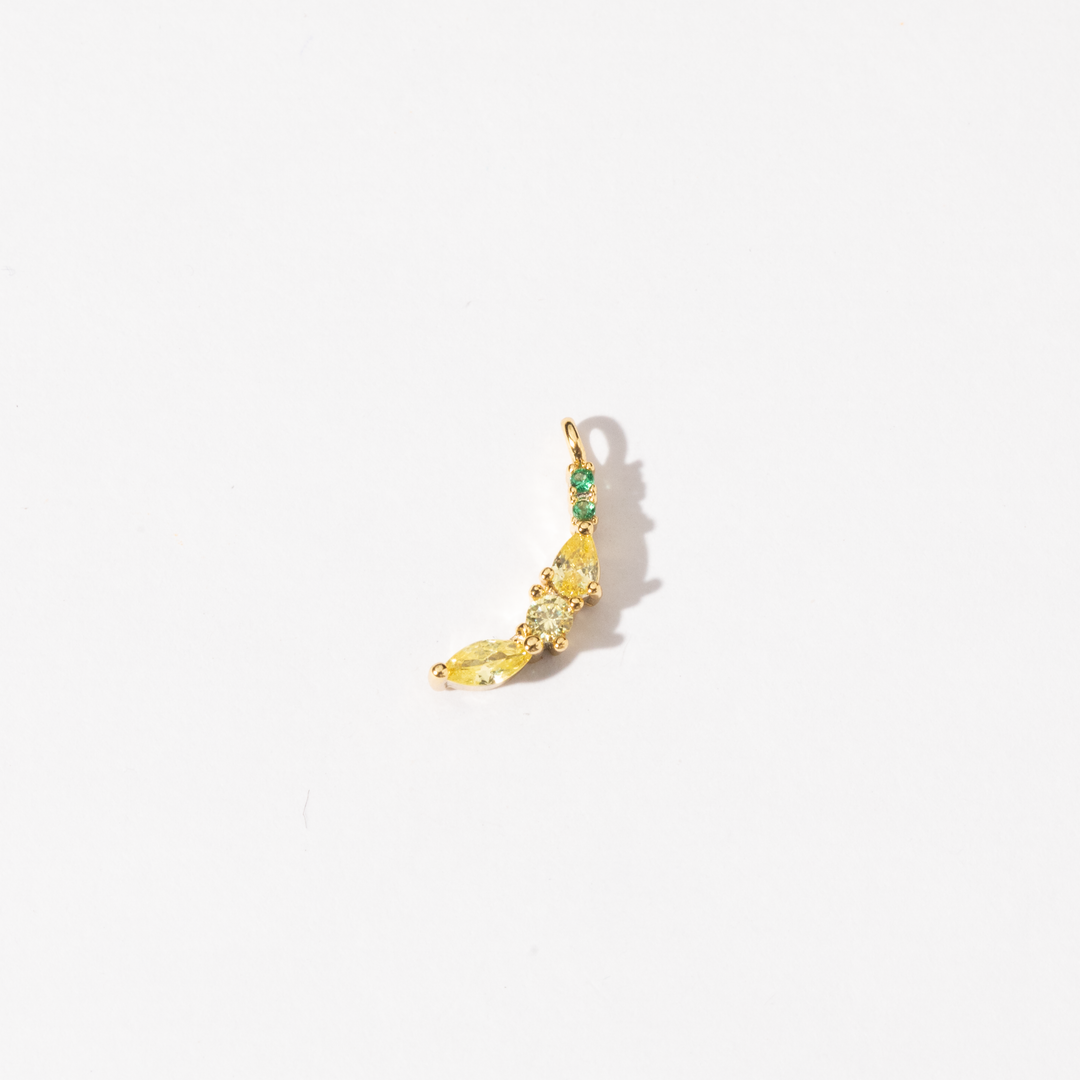 A handmade gold plated stainless steel charm with a yellow and green cubic zirconia in the shape of a banana.