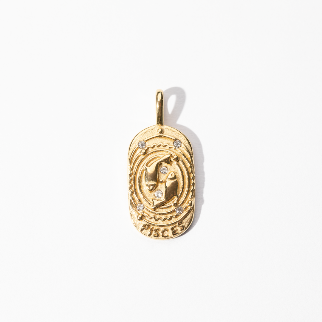 A gold-colored metal medallion charm with the Pisces symbol and small embellishments