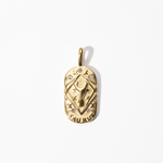 A gold-colored engravable Taurus medallion charm with intricate designs and small embellishments.