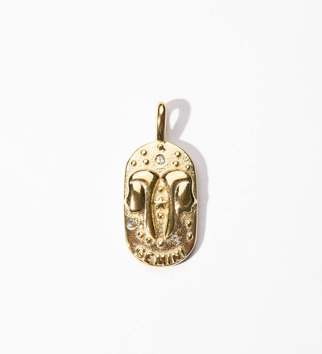 A gold-colored metal medallion charm with an engraved celestial design, symbolizing the zodiac sign Gemini.