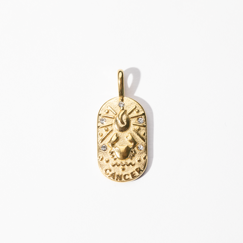 A gold-colored metal medallion charm with a Cancer zodiac symbol, featuring intricate celestial design.