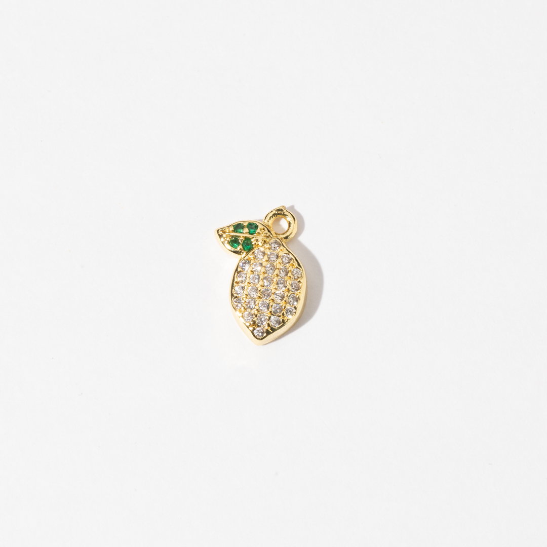 A Personalized gold-plated charm Jewelry in the shape of a lemon, adorned with clear zirconia stones and green gem leaves.