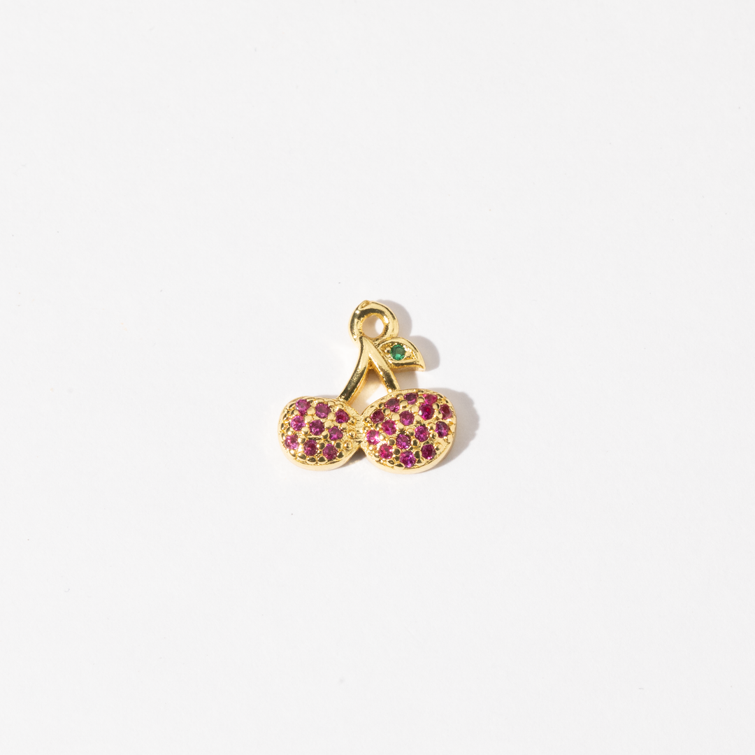 A custom made gold plated stainless steel charm in the shape of two cherries with red zirconia paving and a green gem leaf.