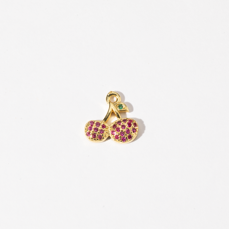 A custom made gold plated stainless steel charm in the shape of two cherries with red zirconia paving and a green gem leaf.