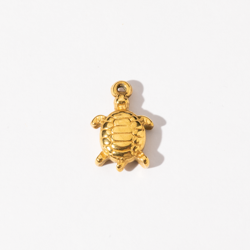 A gold-colored stainless steel turtle charm against a white background.