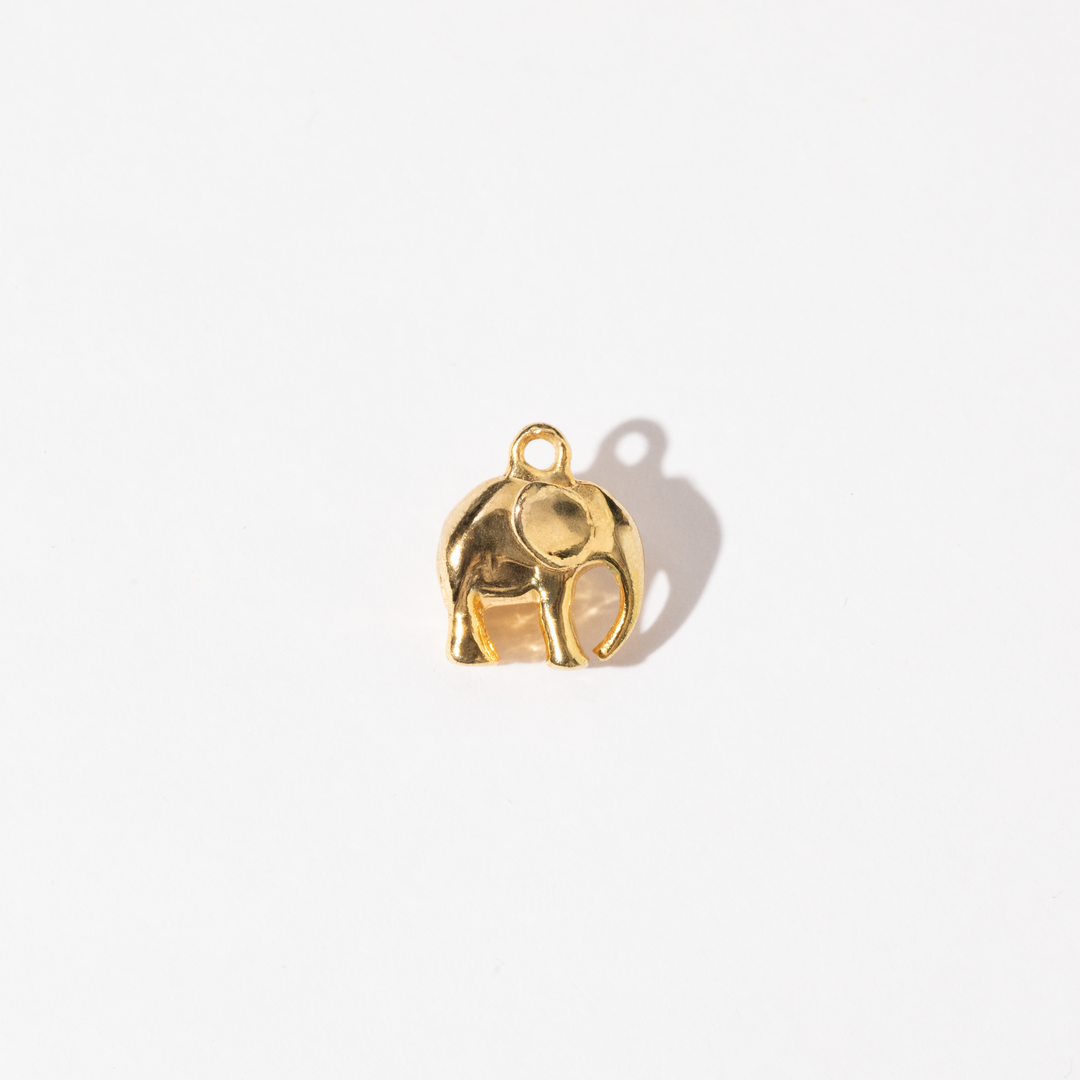 A gold-colored metal charm shaped like an elephant.