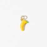 A gold plated stainless steel charm in the shape of a banana with yellow and green tones.