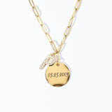 A gold paperclip chain necklace with a gold coin charm personalized with text and a pavé initial.