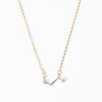 A dainty necklace with a gold chain and a charm featuring a zodiac constellation, adorned with small white crystals.