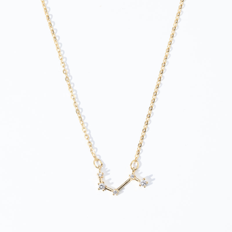A dainty necklace with a gold chain and a charm featuring a zodiac constellation, adorned with small white crystals.