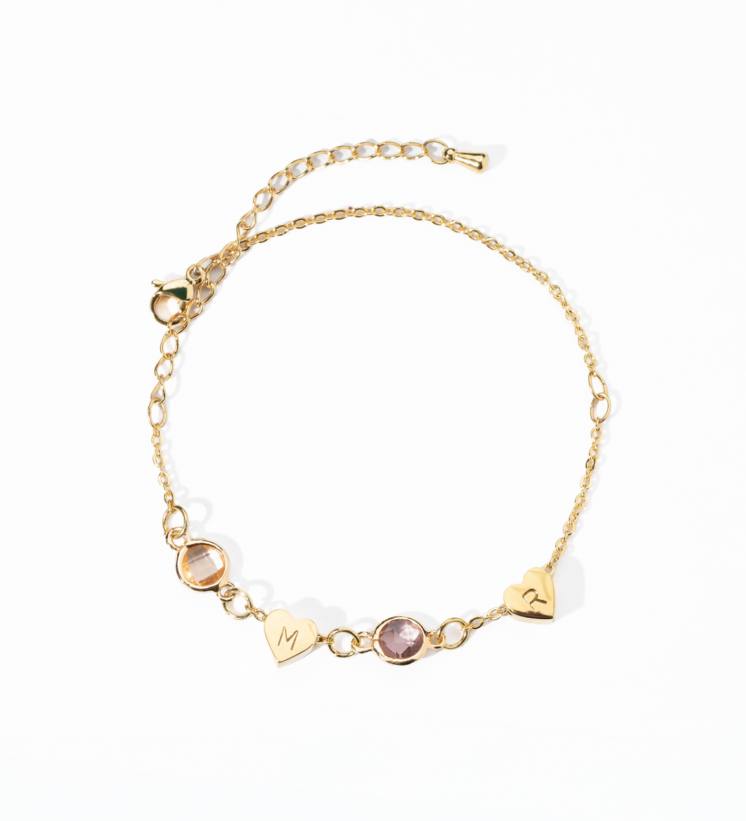 A personalized gold-colored bracelet featuring a heart-shaped charm and a birthstone, attached to a chain with a extender chain.