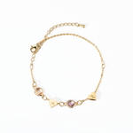 A personalized gold-colored bracelet featuring a heart-shaped charm and a birthstone, attached to a chain with a extender chain.