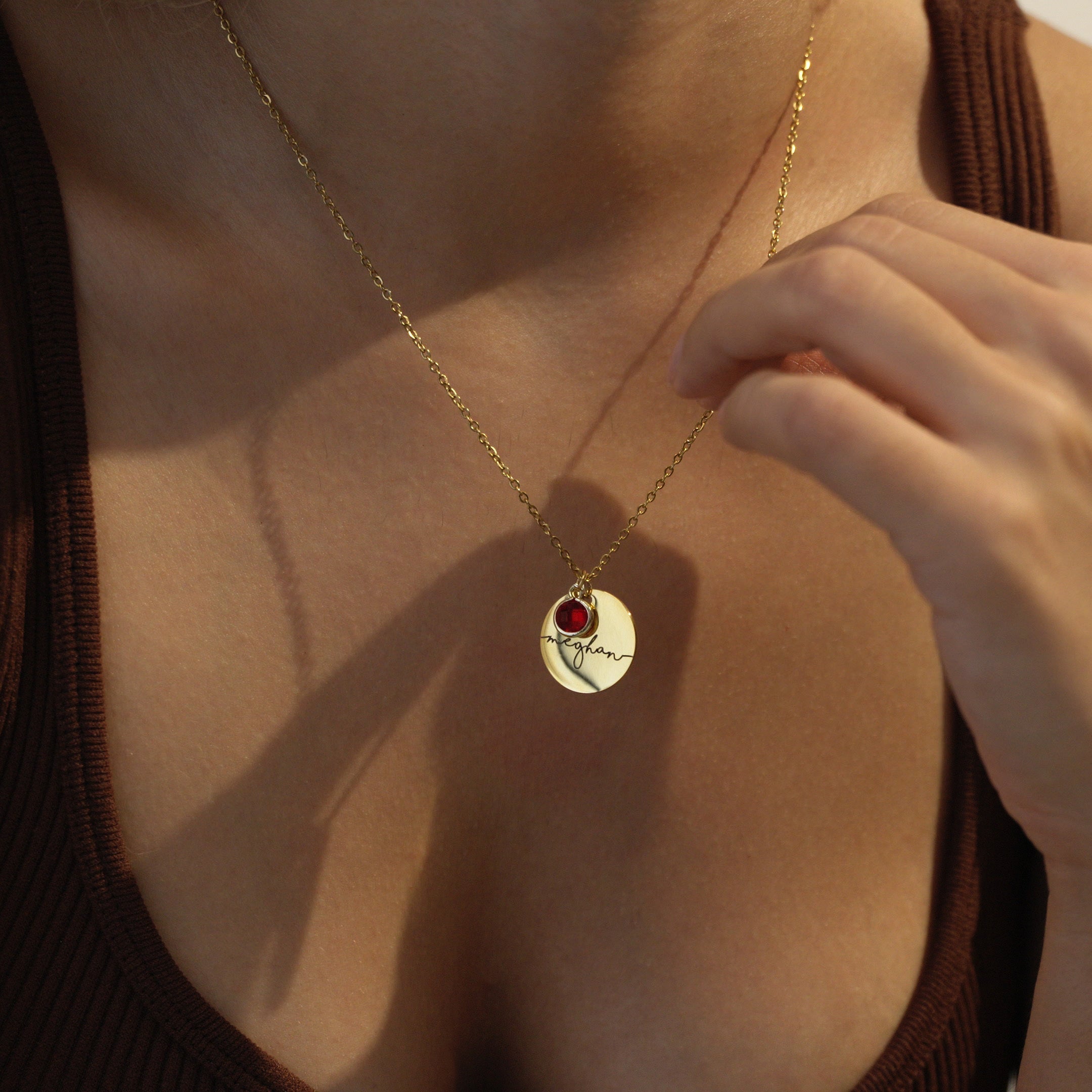 Gold necklace with a Personalized pendant worn by a person against a neutral background