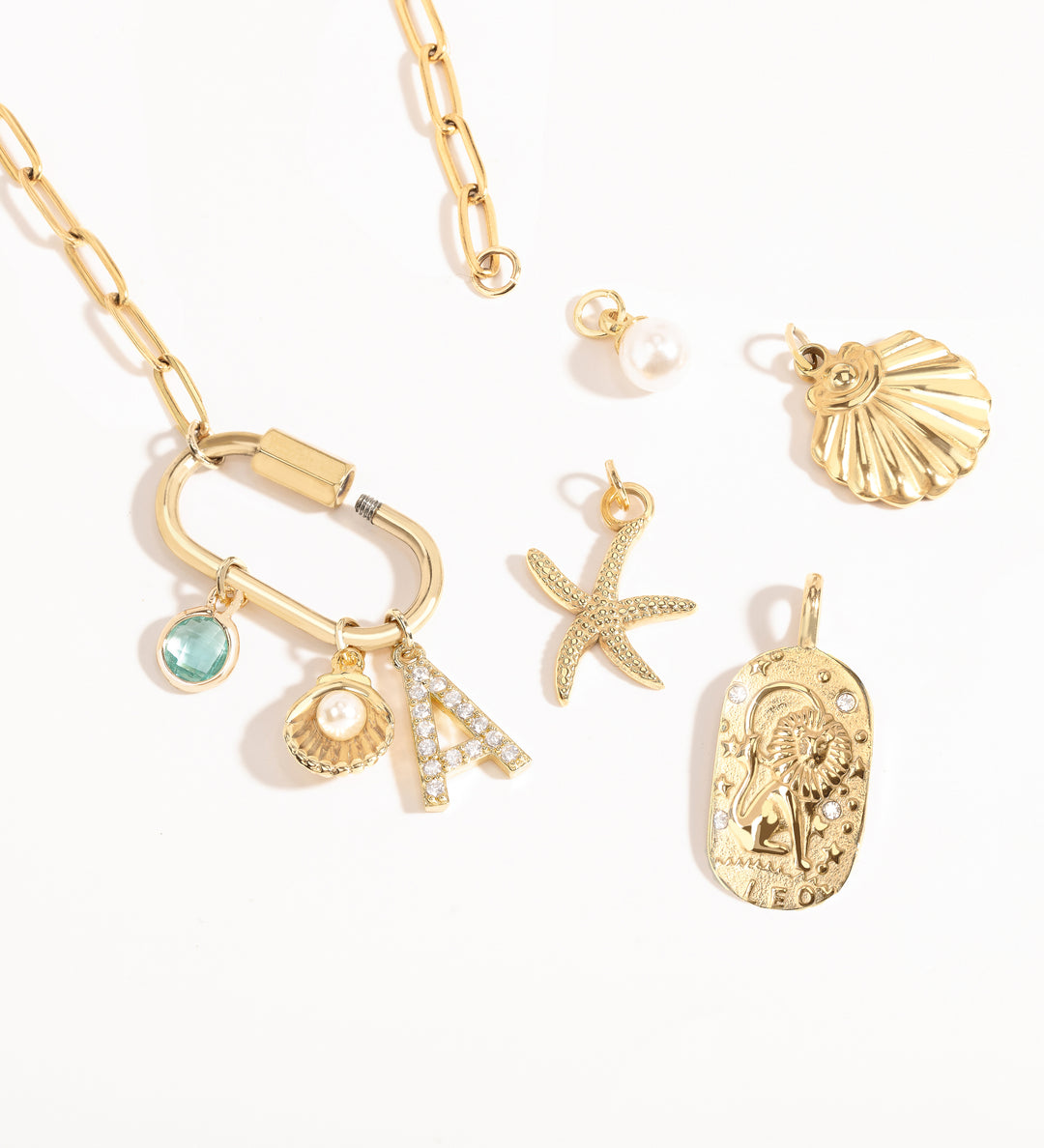 A Customize collection of gold-plated charms with travel-themed details, including a camera, suitcase, and airplane, accompanied by a gold chain and other small accessories.
