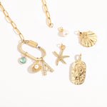 A Customize collection of gold-plated charms with travel-themed details, including a camera, suitcase, and airplane, accompanied by a gold chain and other small accessories.