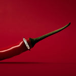 A personalized dainty initial ring with a red hot chili pepper design, with a gold finish, against a red background.