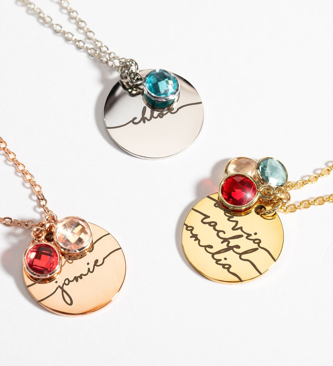 A series of three necklaces showing different styles with birthstone charms and personalized engraved names. Each necklace has a metallic finish and a chain.