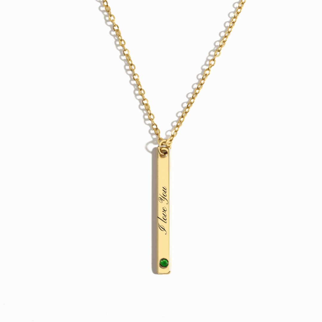 Personalized gold vertical bar necklace featuring a custom engraving and a birthstone accent at the bottom, hanging from a delicate gold chain.