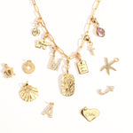 A collection of various charms including a heart, a star, and initial charms, attached to a gold-tone chain necklace.