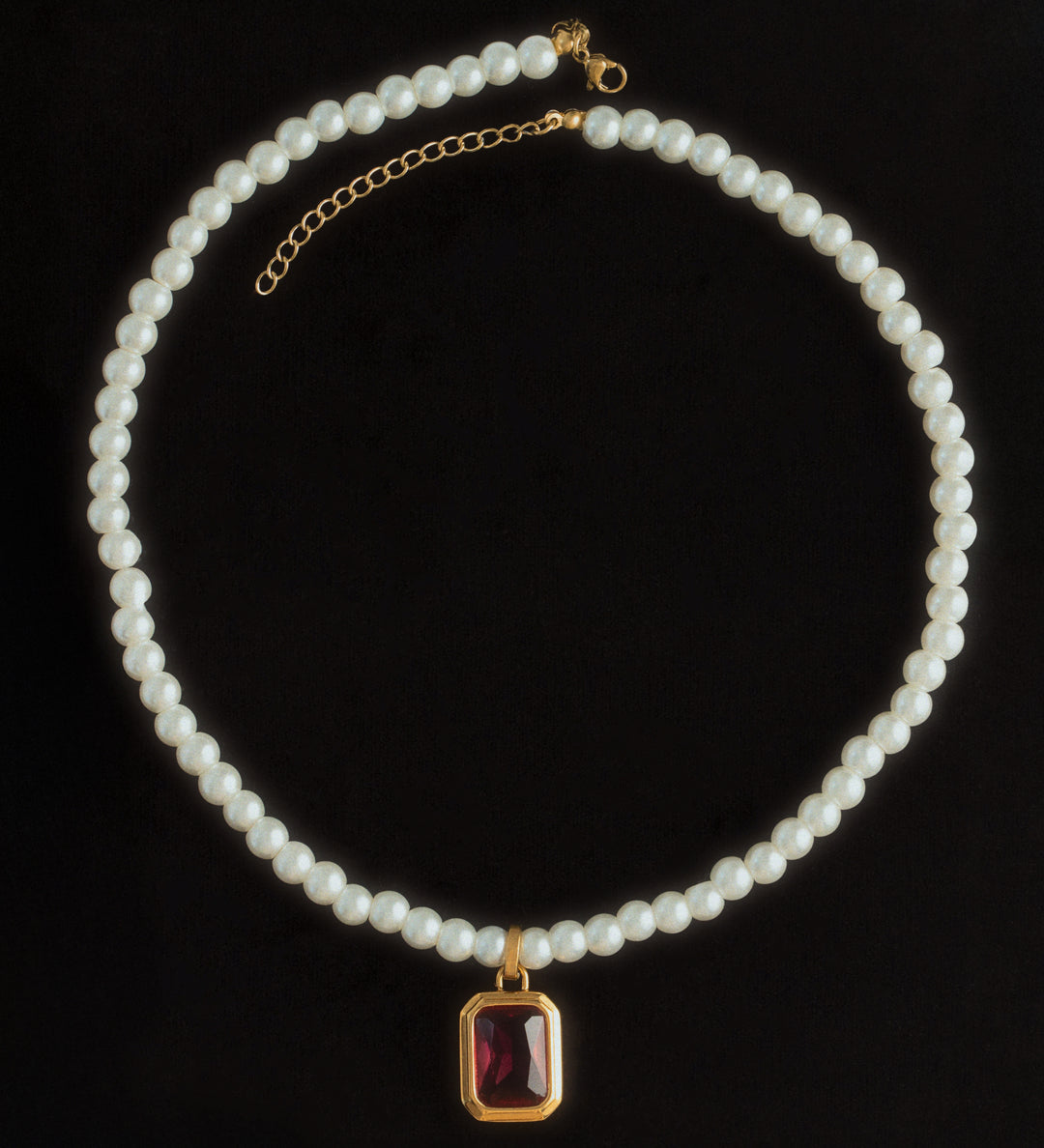 A pearl birthstone necklace with a gold-colored clasp and a purple birthstone pendant, displayed against a black background.